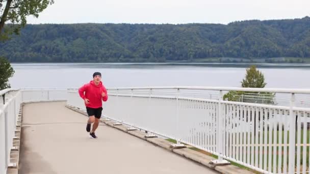 Ein Läufer Farbiger Kleidung Läuft Frühmorgens Über Eine Brücke Und — Stockvideo