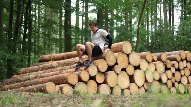 アジア人の男が森の建設現場 Restのために薪の上に休んでいる 高品質の4K映像 — ストック動画