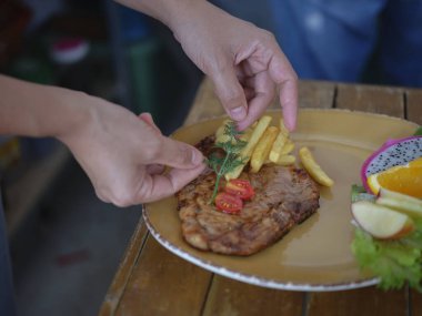 Chefs hand prepares a Grilled pork ribs  and decorates  hearb