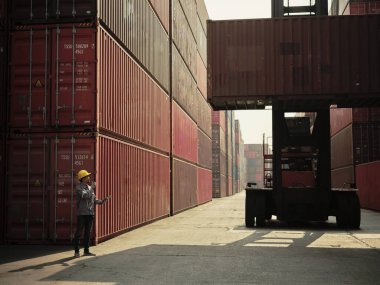 Güvenlik kaskı takan Asyalı işçiler, Lojistik İthalat İhracat arka planı için konteynır kargo gemisinin önündeki konteynır ekibiyle iletişim kuruyor..