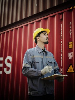 Mühendis OR Worker konteyner kargo deposunda güvenlik denetimi ve denetimi sırasında kontrol listesi belgesini yazıyor ve kontrol ediyor