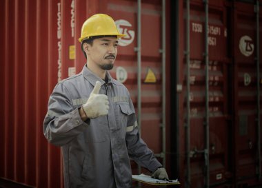 Mühendis OR Worker konteyner kargo deposunda güvenlik denetimi ve denetimi sırasında kontrol listesi belgesini yazıyor ve kontrol ediyor