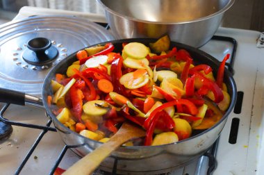 Homemade cooking of mixed fried vegetables comprising red peppers, potatoes, courgettes and carrots in a stovepan