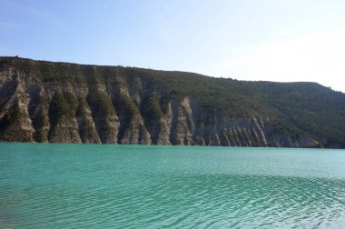Fransa 'nın Alpes-de-Haute-Provence kentindeki Castillon Gölü' nün mavi turkuaz sularına dağ kayalıkları düşüyor.