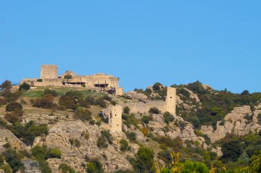 Fransa 'nın güneyindeki kayalık bir çıkıntının tepesindeki antik, ortaçağ tahkim edilmiş bir şatonun kalıntıları; manzara Vaucluse' daki Mornas kalesine çok benzer (Provence-Alpes-Cote-d 'Azur)