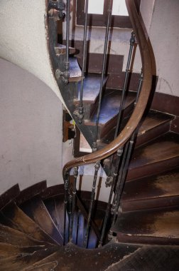 Toulouse, Fransa 'nın tarihi şehir merkezindeki eski bir apartmanın içindeki ahşap ve metal bir tırabzanla donatılmış, sıkıntılı basamakları olan antik bir ahşap merdiven.