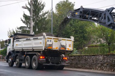 Albi, Fransa - Ağustos 2021 - Yol bakımı sırasında soğuk değirmen makinesi tarafından kaldırılan eski kaldırım taşıma bandından bahşiş veren beyaz bir kamyonet aldı.