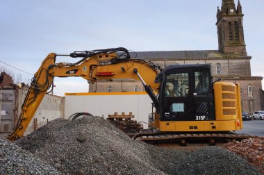 Villefranche d 'Albigeois, Fransa - 2021 - Amerikan üreticisi Caterpillar tarafından yapılan sarı bir kazıcı (hidrolik destek), köy kilisesinin önündeki bir inşaat sahasında