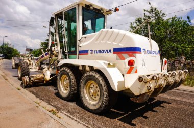 Tarn, Fransa - Mayıs 2020 - Fransız inşaat şirketi Eurovia (Vinci) tarafından işletilen ve ön dingile monte edilmiş iki derecelendirme bıçağı ve bir sırt deşicinin yer aldığı bir New Holland motor gradyatörünün arka görüntüsü