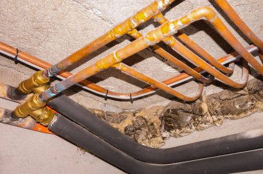 Şehir gazına bağlı merkezi ısıtma sisteminin propan tedariği için polistiren ambalaj ve kaynak izlerine sahip bakır ve pirinç borular, evin bodrumuna yerleştirildi.