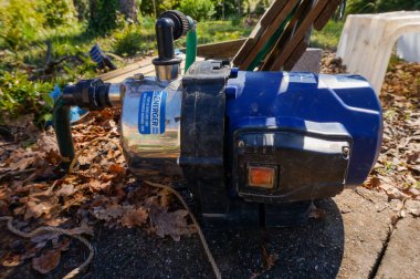 Occitanie, Fransa - Nisan 2020 - Açık havaya kurulmuş organik bir sebze bahçesinin sulama sistemi için bir hortumla bir kuyuya bağlı bir elektrik yüzey pompası