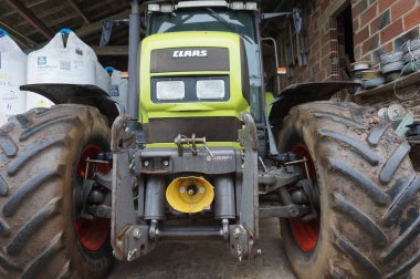Teillet, Fransa - Kasım 2021 - Tekerlekler, ön bağlantı ve güç kalkış sistemi Hollandalı üretici Zuidberg 'den, Alman üretici Claas' ın tarımsal traktörüyle, bir ahırın içine park edilmiş