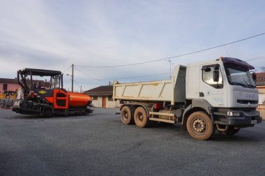 Tarn, Fransa - Şubat 2021 - Otoparkta yol çalışması için inşaat malzemeleri: önde beyaz, altı tekerlekli bir Renault bahşiş kamyonu ve arkada bir Volvo ABG asfalt kaldırıcı