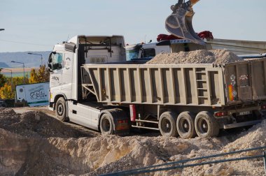 Reims, Fransa - Ekim 2022 - URCA 'nın Moulin de la Housse bilim kampüsündeki şantiye: Pist monte edilmiş bir Liebherr kazıcısı temel kazıyor ve dünyayı bir inşaat kamyonunun bahşiş veren aracına boşaltıyor
