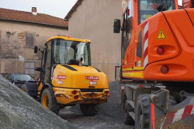 Tarn, Fransa - Şubat 2021 - Bir şantiyede iki tekerlekli inşaat makinesi: Colas tarafından işletilen turuncu bir Liebherr kazıcısı ve Loxam tarafından kiralanan sarı eklemli bir yükleyici