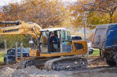 Reims, Fransa - Kasım 2022 - Alman-İsviçreli imalatçı Liebherr 'den sarı bir kazıcı bir çukur kazıyor ve dünyayı bir bahşiş karavanına boşaltıyor, URCA Kampüsü' ndeki bir şantiyede.