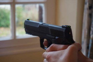 Occitanie, France - Dec. 2021 - Firmly holding the grip, a shooter aims a HDP 50 T4E, a CO2 air gun, towards a target clipart