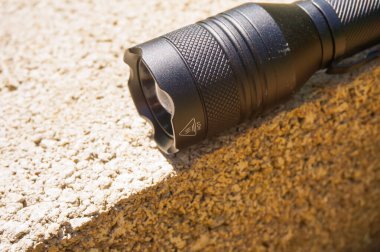 Yüksek kaliteli ve güçlü bir Çin yapımı el fenerinin ucu, cam kırıcı olarak kullanılacak crenelleştirilmiş bir ucu, LED 'in ışığını ve alüminyum gövdeyi yönlendirecek optik bir bloğu içeren yakın görüş