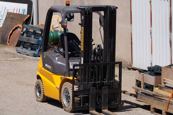 Albi, France - July 2022 - A yellow and black, made-in-France MI25G forklift from the Pays de la Loire-based manufacturer Manitou, parked in the courtyard of a storage unit among miscellaneous goods