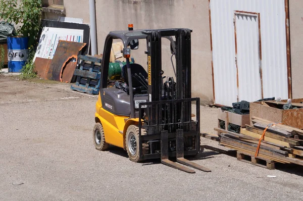 Albi, Fransa - Temmuz 2022 - Fransa yapımı sarı ve siyah bir MI25G forklift Pays de la Loire merkezli üretici Manitou 'dan, çeşitli malların arasında bir deponun avlusuna park edilmiş