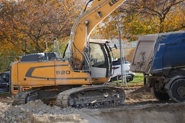Reims, Fransa - Kasım 2022 - Alman-İsviçreli imalatçı Liebherr 'den sarı bir kazıcı bir çukur kazıyor ve dünyayı bir bahşiş karavanına boşaltıyor, URCA Kampüsü' ndeki bir şantiyede.