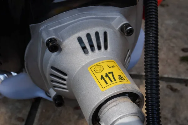 全新汽油刷锯燃烧发动机输出处的驱动轴和冷却架末端 并附有钢制变速箱分贝的噪音指示 — 图库照片