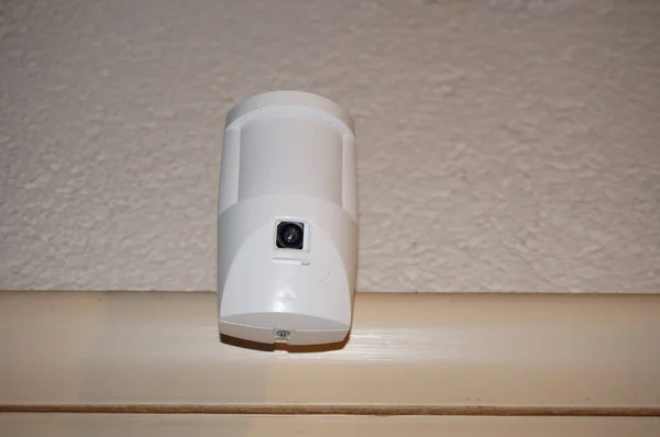 ドアフレームに固定された接続された家の警報および遠隔監視のシステムの一部として監視カメラが装備されている動き検出器 — ストック写真
