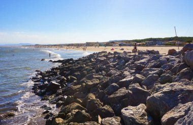 Güney Fransa 'da bir sahil beldesi olan Narbonne-Plage sahilinden görülen Akdeniz' in derin mavi sularında dalgalar ufukta Pyrnes Dağları 'nın sırtı görülebilir.