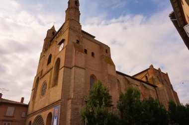 Fransa 'nın Rabastens kentindeki 700 yıllık Güneyli gotik UNESCO Dünya Mirasları Alanı Notre-Dame du Bourg' un görkemli kilisesinin yan görüntüsünde iki tepe noktası olan dev bir tuğla çan kulesi yer alıyor.