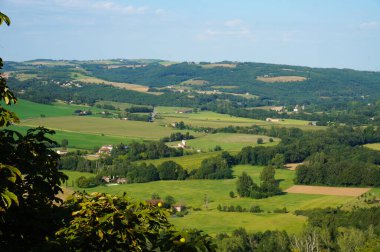 Fransa 'nın güneyindeki Albigeois ve Gaillacois kırsallarındaki Cordes-sur-Ciel kentinden görülen kırsal manzara: arazi, uzaklardaki tarım evleri ve tepelerle benekli tarımsal alanlara sahiptir.