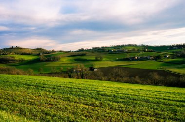 Fransa 'nın muhteşem kırsal kesimlerinde bulutlu bir gün. Yeşil alanlar, ağaçlık tepeler ve vadiler ve Occitanie' nin kırsal ve tarımsal alanlarında birkaç çiftlik ya da kır evi.
