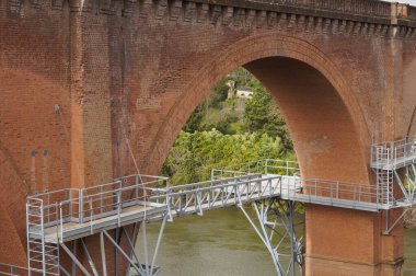 Ocak 2021 'de Fransa' nın Albi kentinin gelecekteki iskelesinin inşaatında, Tarn Nehri 'nin suyunun üzerinde asılı duran metal iskelet, eski bir demiryolu viyaoluğunun kemerlerinin altında inşa edildi.