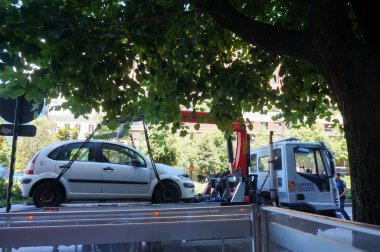 Toulouse, Fransa - 10 Haziran 2023 - Yasadışı park halindeki bir araca el konuldu: Bir kamyondaki vinç ile çekilerek çekiliyor, tekerleklere bağlı halatlarla kaldırılıyor.