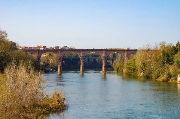 The brick, arched railway viaduct of Albi, or Castelviel Bridge, in the South of France ; built in the 19th century, it crosses the blue water of the River Tarn and connects its two leafy banks
