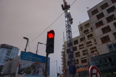 Hauts-de-Seine, Fransa - Aralık 2020 - Paris 'in banliyölerinde inşaat halindeki beton bir binanın çalışma alanına hükmeden beyaz ışık projektörlü bir kule vincinin düşük açılı görüntüsü