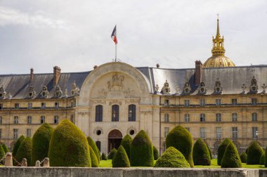 Paris, Fransa - Temmuz 2019 Klasik tarz Hotel des Invalides 'in ön cephesi, Fransız bayrağı, parkı, çalıları ve Ordu Müzesi' nin kasa kapısına giden kaldırımlı yol.