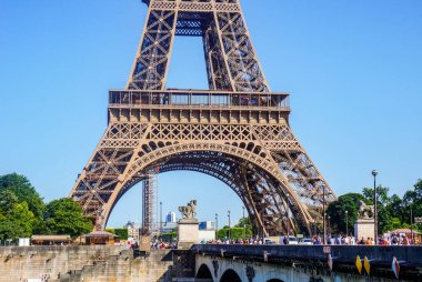 Paris, France - June 2019 - The crowded arch bridge Pont d'Ina, full of tourists, over the River Seine at the foot of the world-famous Eiffel Tower, the highly touristy symbol of the French capital