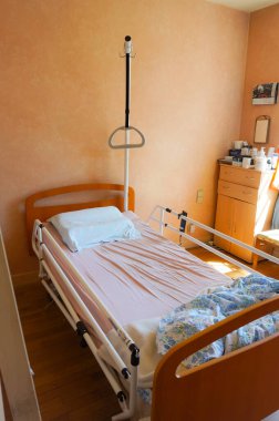 Occitanie, Fransa - Mayıs 2020 - Evde bakım için tıbbi malzeme: hastanın ayağa kalkmasına yardım etmek için yanal bariyerler ve trapezden oluşan mekanize bir hastane yatağı ile donatılmış yaşlı bir kişi odası