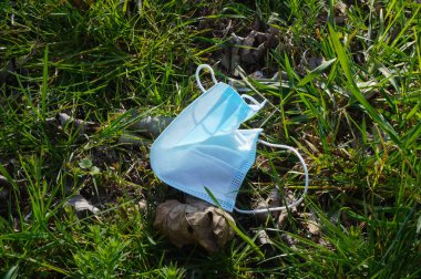 Cerrahi yüz maskesi vahşi doğada terk edildi, Coronavirus salgınının ortasında çimlere atıldı; çevreyi kirletmenin gösterimi