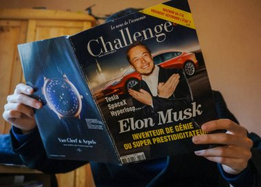 Tarn, Fransa - Şubat 2019 - Bir adam, Fransız ekonomi gazetesi Challenges 'ın bir sayısını okuyor. İş adamı Elon Musk' u bir Tesla 'nın önünde, arkasında lüks bir saat markası reklamı ile gösteriyor.