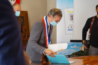 Crest, Fransa - Ekim 2021 - Belediye Başkanı Herve Mariton, üç renkli bir tasma takıyor, bir sivil düğün töreni sırasında belediyede bazı evrakları imzalıyor; kendisi Başkan Sarkozy 'nin altında eski bir bakan.