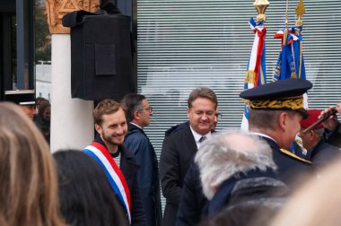 Toulouse, Fransa - Mayıs 2023 - Franois Piquemal Ulusal Meclisi üyesi, gülümseyerek ve resmi üç renkli kuşağı takarak, bir anma töreninin kenarındaki insanları selamlıyor.