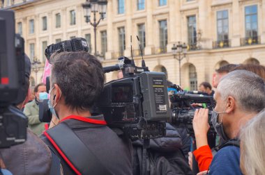 Paris, France - Oct. 10, 2020 - Among a group of reporters, a journalist of France Television public channels, covers a manifestation of Marchons Enfants against the bioethics bill with a TV camera clipart