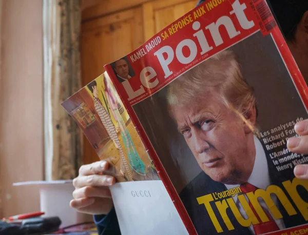 Tarn, Fransa - Şubat 2019 - Bir adam haftalık Fransız gazetesi Le Point 'in sayısını elinde tutuyor ve okuyor, ön sayfada Başkan Donald J. Trump' ın portresi ve arka sayfada Gucci 'nin reklamı yer alıyor.