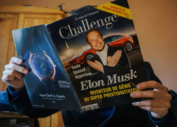 stock image Tarn, France - Feb. 2019 - A man reads an issue of the French economic newspaper Challenges showing the businessman Elon Musk in front of a Tesla, with an advert for a luxury watch brand on the back