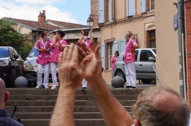 Albi, Fransa - 17 Temmuz 2021 - Pembe paltolu kadın hemşire yardımcıları zorunlu aşı ve sağlık iznine karşı tezahürat yaptılar ve buna karşılık protestocular tarafından alkışlandılar.