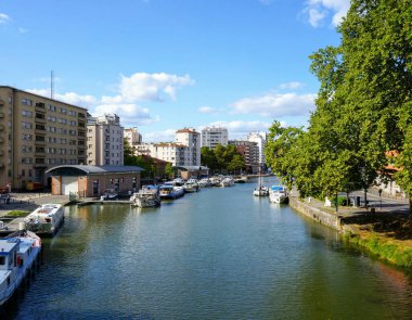Fransa 'nın Toulouse kentindeki Saint-Sauveur Limanı' nda bulunan nehir limanı ve limanı, Canal du Midi 'ye demir atan tekne ve mavnalar ve sahildeki apartman binaları.