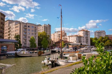 Fransa 'nın Toulouse kentindeki Canal du Midi kanalı yakınlarındaki Saint-Sauveur limanında demirlemiş ve Le Busca ve Saint-Aubin yerleşim bölgelerinin apartman binaları ile çevrelenmiş durumda.