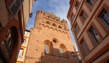 Perspective of Rue du Taur, a historical street in the centre of Toulouse, in the South of France, lined with old, traditional brick houses and towered by the bell-tower of Notre-Dame du Taur Church