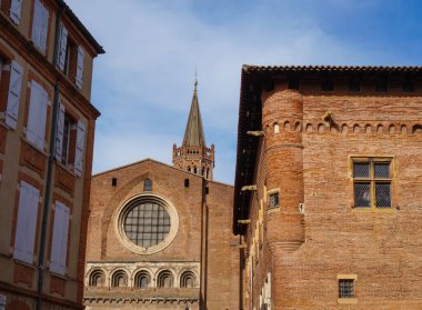 Perspective of Rue du Taur, a historical street in the centre of Toulouse, in the South of France, lined with old, traditional brick houses and towered by the bell-tower of Notre-Dame du Taur Church
